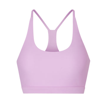 Classic racerback sports bra in light pink with seamless fit and removable padding. Perfect for light workouts and everyday wear, ghost image front view